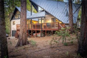 a large house with a metal roof in the woods at Modern Mountain Luxury Soak, Stay, & Be Spoiled in Shaver Lake