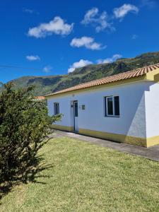 una casa blanca con montañas al fondo en Casa do Baixio, en Faja Grande