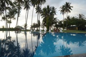 a large swimming pool with palm trees in the background at Langkah Syabas Beach Resort in Kinarut