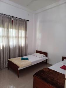 a bedroom with two beds and a window at Yelona Rest in Galle