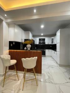 a kitchen with white cabinets and two white chairs at Villa súper cómoda 3 habitaciones con piscina in Juan López