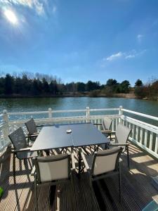 a table and chairs on a deck next to the water at Le Cottage de Belle Dune in Fort-Mahon-Plage