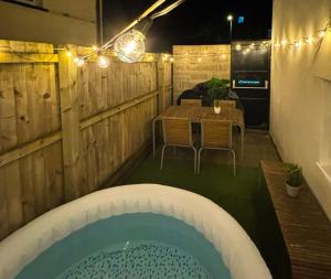 a backyard with a pool and a table and chairs at Duplex Stay With Hot Tub Opposite Stadium in Cardiff