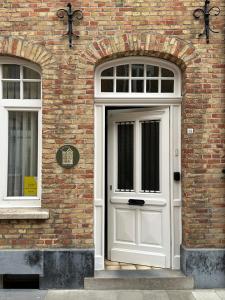 a white door on a brick building with two windows at In De Wulf in Ypres