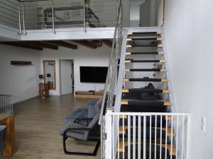 a staircase in a room with a couch and a tv at Ferienwohnung Sonnenaufgang im Ruppiner Land in Kränzlin +18 photos