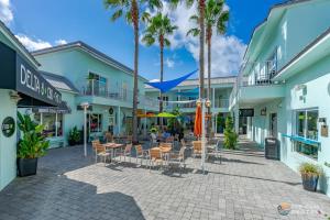 a patio with tables and chairs and palm trees at Stay ON Flagler Avenue! Charming Condo with Full Kitchen, Parking and Courtyard! in Chicken Island