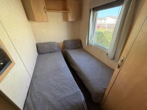 a small room with two beds and a window at Seaside Caravan in Leisure Park with WiFi & Parking with decking 2 bedrooms in Rhyl