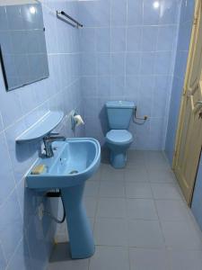 une salle de bain avec un lavabo bleu et des toilettes dans l'établissement Maison moderne à Calavi - paisible et confortable, à Abomey-Calavi
