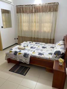 - une chambre avec un lit et une fenêtre avec un rideau dans l'établissement Maison moderne à Calavi - paisible et confortable, à Abomey-Calavi