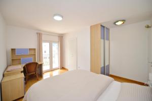 多布罗塔SEA VIEW apartment 2km from the Old Town of Kotor的卧室配有白色的床、书桌和窗户。