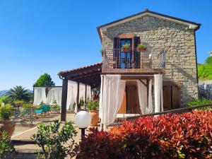 a stone house with a balcony and flowers at La Valle Del Sole Country House in SantʼIppolito +93 photos