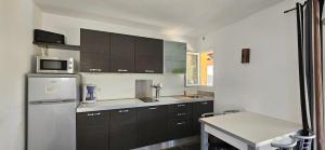 eine Küche mit schwarzen Schränken und einem weißen Kühlschrank in der Unterkunft Studio Dolce & Vita C2 vue mer avec piscine in Propriano