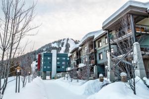 a snow covered street with buildings and a mountain at Slalom Creek 2 Bedroom & Den in Rossland +4 photos