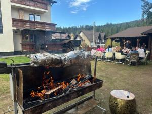 a grill with fire in a yard with a group of people at Pensiunea La Ancuța-n Bucovina in Voronet