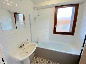 ein weißes Badezimmer mit Waschbecken und Badewanne in der Unterkunft Beau studio - vue magnifique - pied des pistes in Enchastrayes