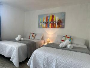 a bedroom with two beds and a painting on the wall at Casa Lirios in Las Victorias