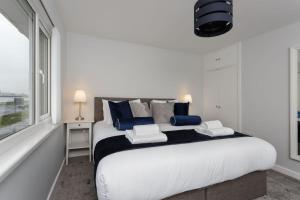 a white bedroom with a large bed with blue pillows at Castle View - 2 Bed Stylish Coastal Port Solent Retreat with Views! Parking, Sleeps 6 - By Blue Puffin Stays in Portsmouth