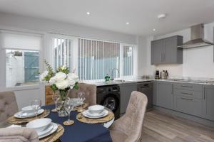 a kitchen with a table with plates and flowers on it at Castle View - 2 Bed Stylish Coastal Port Solent Retreat with Views! Parking, Sleeps 6 - By Blue Puffin Stays in Portsmouth