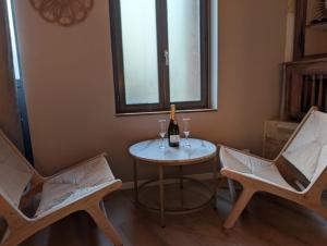 a table with two chairs and a bottle of wine at Suite avec jacuzzi privatif in Vergèze