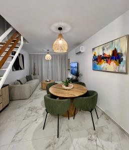 a living room with a table and green chairs at FatCow Beach Apartment Ultra in Larnaka