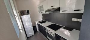 a small kitchen with a stove and white cabinets at Stylish 1-bedroom apartment for 3 with balcony, free parking & river views in a quiet area in Prievidza