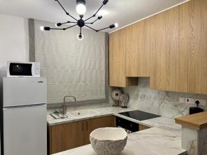 a kitchen with a white refrigerator and wooden cabinets at FatCow Beach Apartment Ultra in Larnaca +26 photos