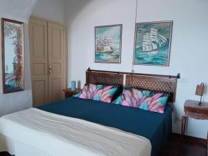 a bedroom with a blue bed with paintings on the wall at Villa MariaRosa in Lipari