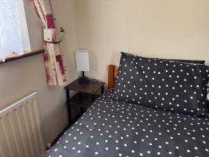 a bed with a polka dot pillow and a lamp at Rusty Cottage in Blacklion