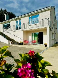 a house with red chairs and a balcony at Fintra Bay Hideaway in Killybegs
