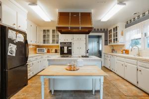 a kitchen with white cabinets and a black refrigerator at Kaleidoscope Inn & Gardens in Nipomo
