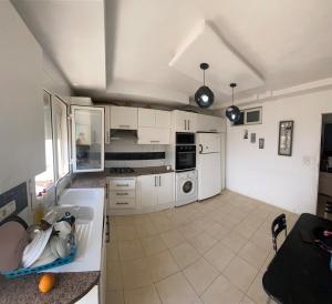 a large kitchen with white cabinets and appliances at Maison Chkili in Kelibia