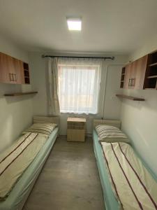 two beds in a small room with a window at Pompa Apartman in Nyíregyháza