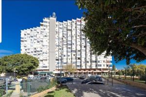Un gran edificio blanco con coches aparcados en un estacionamiento. en Estudio vistas campo golf y piscina, en Torremolinos