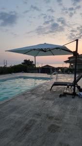 a chair and an umbrella next to a swimming pool at Mediterraneo Suites with Pool & Sea View Escape in Nea Kalikratia