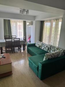a living room with a green couch and a table at VIRGO Apartaments Mamaia in Mamaia