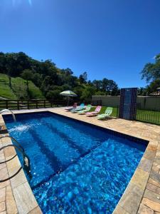 a swimming pool with blue water in a yard at Villa Mantiqueira SFX - Suítes in São Francisco Xavier