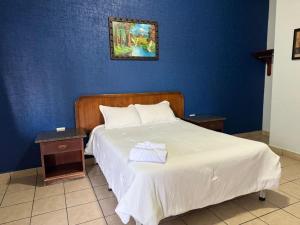 a bedroom with a white bed with a blue wall at Rio inn in Delicias