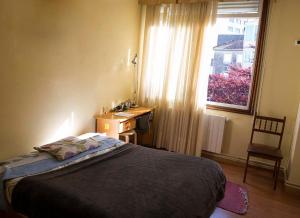 1 dormitorio con cama, escritorio y ventana en Hostal A Pedra en Vigo