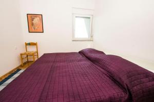a purple bed in a white room with a window at Apartments More in Kožino