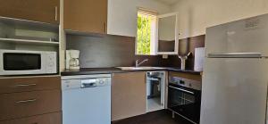 a kitchen with a refrigerator and a microwave at T3 Dolce & Vita D5 avec Piscine et vue Montagnes in Propriano