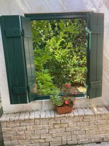 a window with green shutters and potted plants on a brick wall at Barbat 249 in Barbat na Rabu