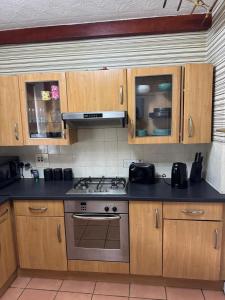 a kitchen with wooden cabinets and a stove top oven at Chic & Cozy 2BR Semi-Detached in Kilmarnock +3 photos