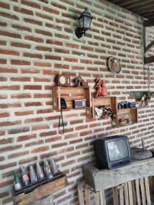 a room with a brick wall with a tv at O Candeeiro - Hostel Acampamento in Arcoverde
