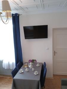 une table avec des chaises bleues et une télévision murale dans l'établissement Vintage EM, à Krosno