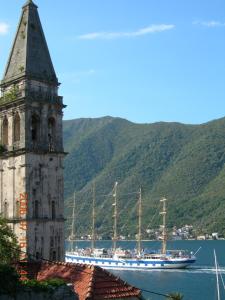 a clock tower with a ship in the water at Painter's House Historic Stone Villa with Sea View in Perast