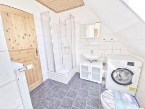 une salle de bain avec une machine à laver et un lavabo dans l'établissement Dünenlounge Dornumersiel, à Dornum 6 autres photos