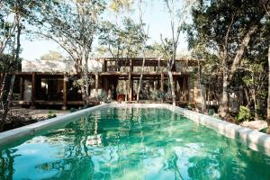 a swimming pool in front of a house with trees at Casa Xul in Tulum
