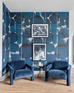 een woonkamer met twee blauwe stoelen en een muur bij Ivy and Ivan at The Lucy by Stay Local Nashville in Nashville