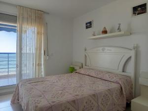 a white bedroom with a bed and a window at Apartamentos GEMA Primera linea Cullera in Cullera