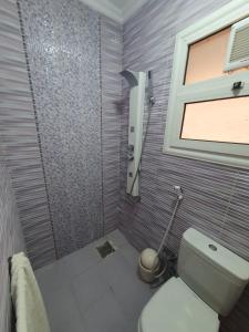 a bathroom with a toilet and a shower with a window at Madinaty modern cozy apartment in Madinaty